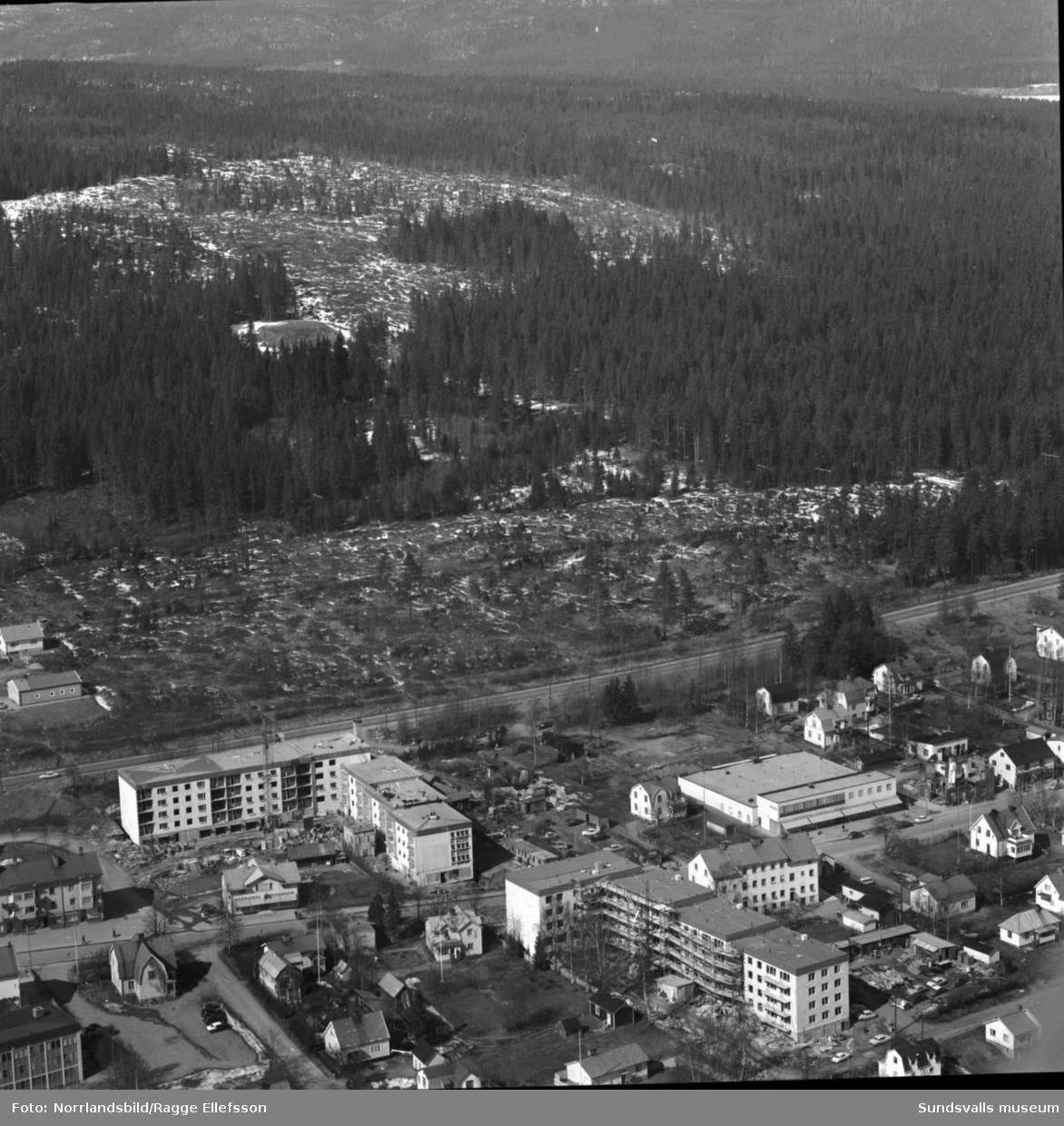 Flygfoto över centrala Timrå med slutspurt på byggen av flerfamiljshus vid Skogsvägen och Köpmangatan.