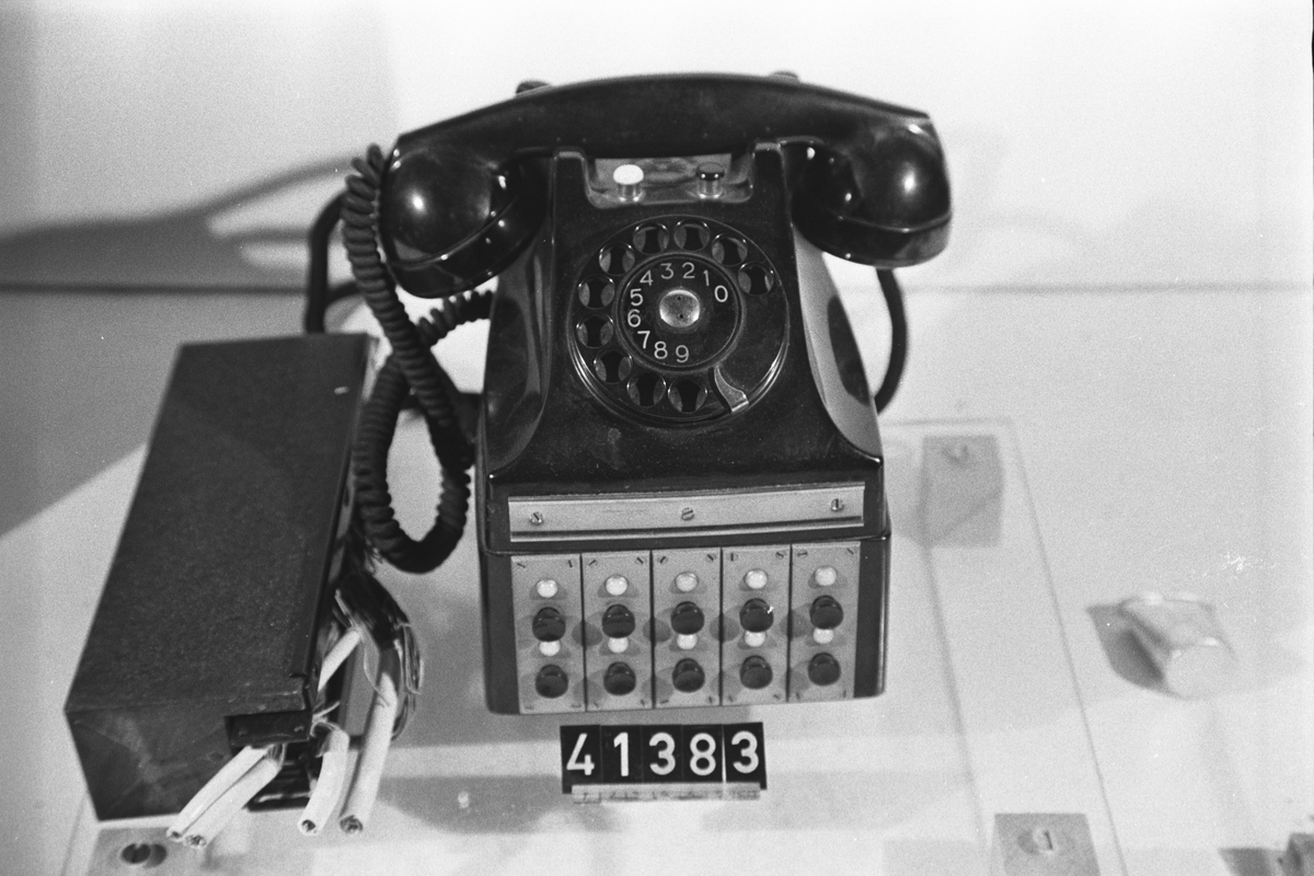Telefonapparat BC 582, 10-nummers linjetagare för AT- och LB-system. Bordapparat av svart bakelit modell m50, sockel med 10 återfjädrande tryckknappar och 10 signallampor där en knapp med intilliggande lampa motsvarar en telefonledning, på apparatens ovansida vit knapp för att i vissa fall avge slutsignal och svart ringknapp för att sända induktorsignal på anslutna LB-ledningar, textilklätt apparatsnöre anslutet till kopplingsplint och på apparatsockelns vänstra sida jack för inkoppling av huvudmikrotelefon. Till apparaten hör ett reläskåp med koordinatväljare där sammankopplingen av ingående apparater och ledningar sker. Upp till 10 linjetagarapparater BC 582 kan anslutas till en anläggning.