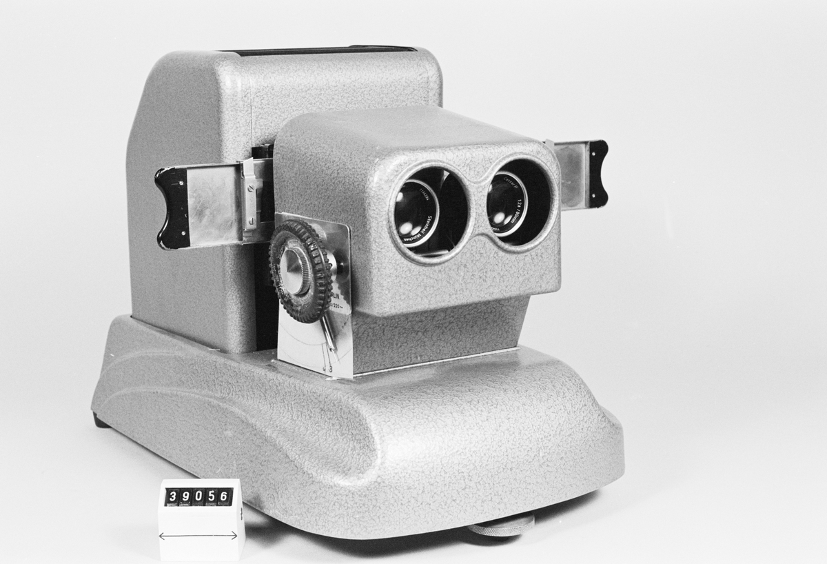 The projector was manufactured by Pintsch Bamag in Berlin in the 1950s. By using polarized light, it is possible to project two images onto the same surface and filter the images to the right eye with polarized glasses. The image for one eye is polarized vertically, the other horizontally.