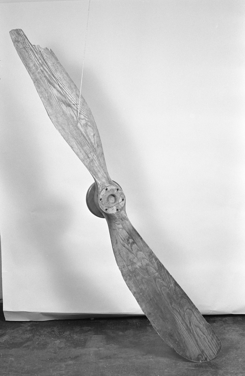 Propeller till flygmaskin med fot i två delar för propellerns montering vid utställningar. Ena bladet avbrutet och spräckt i spetsen.