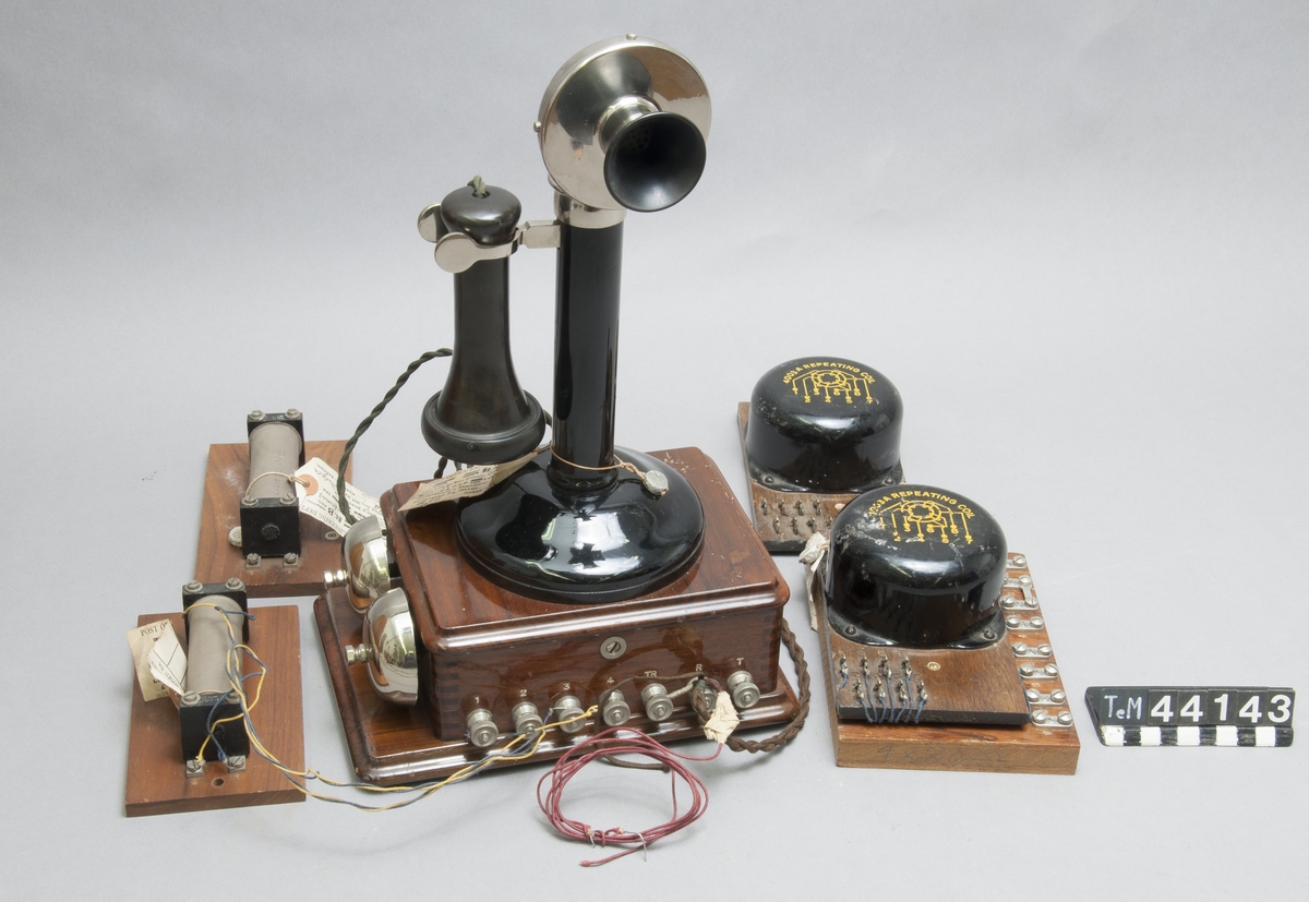 Telefonapparat s.k. ljusstake, i trälåda med två lösa drosslar och två transformatorer på ringkärna träunderdel, med skaft och hörtelefon i bakelit. Fältapparat för CB system.