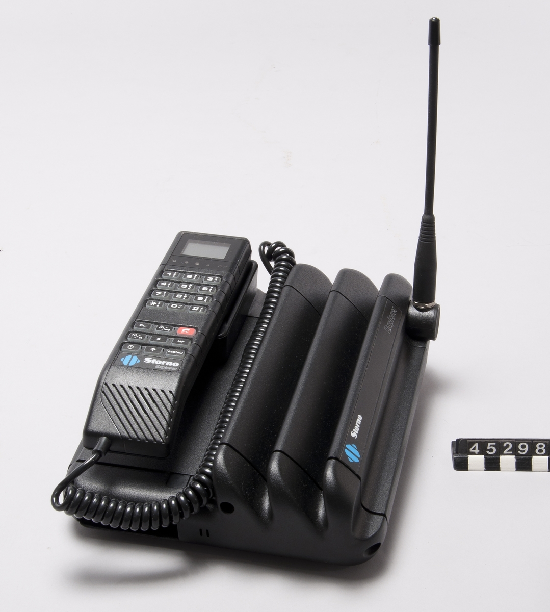 Mobiltelefon Storno Explorer NMT450 med handenhet och basenhet samt antenn.  Den har uppladdningsbart batteri (märkt.CCS2312AVBN, 12v,2,3Ah), kan anslutas till 220V, samt har laddare märkt Motorola Kit no CCPN 4012 A (själva laddaren märkt: MASCOT CCPN 4012A/ 51R02530Z02, Type 8620) och medföljande 12V adapter kontakt för cigarettuttag  Manual ingår.  Basenhet typ S-CCUE2038B ser no 480RTL2545, handenhet typ CCCN3001A ser no 480RTL2545.