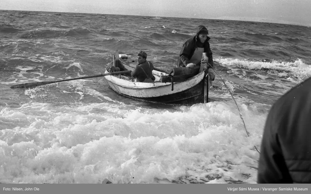 To fiskere som manøvrerer båten i ganske grov sjø inn mot fjæra. Sannsynligvis brødrene Andersen i Gurlouvttgohppi / Godluktbukt. 28. februar 1967.