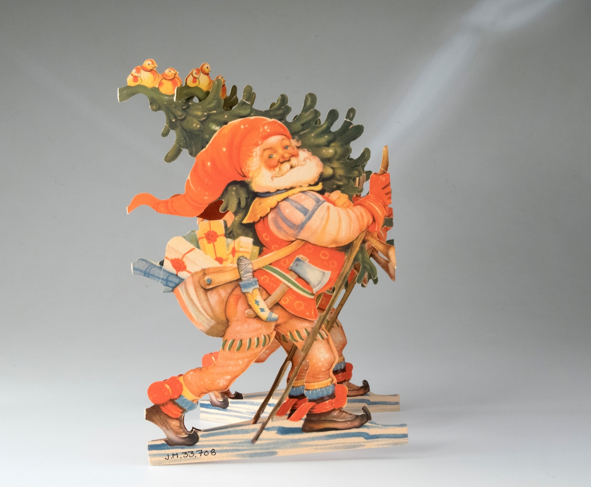 Juldekoration av papper i form av en remsa med silhuettklipp med polykromt tryck på båda sidor. Remsan föreställer tomte som kliver fram med en vandringsstav i sin ena handen och en gran med fåglar på axeln. Över axeln bär tomten också en väska med julklappar, I midjebältet sitter en yxa och en kniv. Tomten bär röd-oranga kläder med dekorationer, och på fötterna näbbskor (samma tryck på fram- och baksida). Remsan har fem tomtar som är placerade två och två mot varandra. Remsan ställs upp i zig-zag-form.