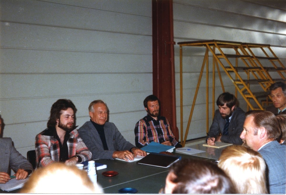 Landskap. Hammerfest. Møtelokale. En gruppe personer, ledelse og tillitsvalgte ansatte i Widerøe, samlet rund et bord i en hangar.