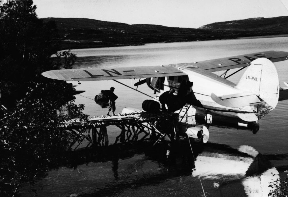 Landskap. Et sjøfly, LN-PAE, av typen Norseman fra Widerøe & Polarfly, fortøyd  i strandkanten.