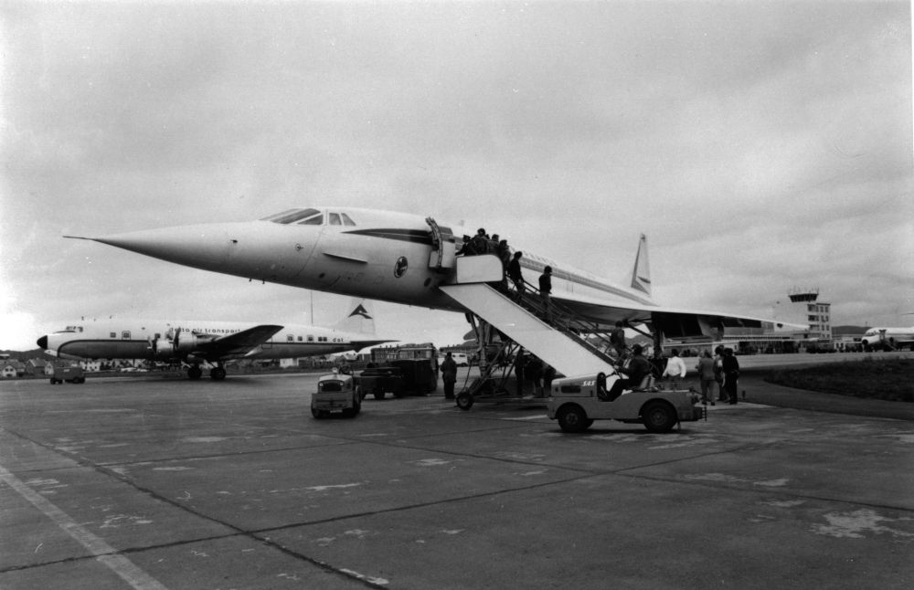 Lufthavn/Flyplass. Bodø. Et fly, Concorde fra Air France, parkert, og stor aktivitet rundt flyet. Ved siden av står et propellfly fra Delta Air Transport parkert. I bakgrunn skimter vi Kontrolltårnet