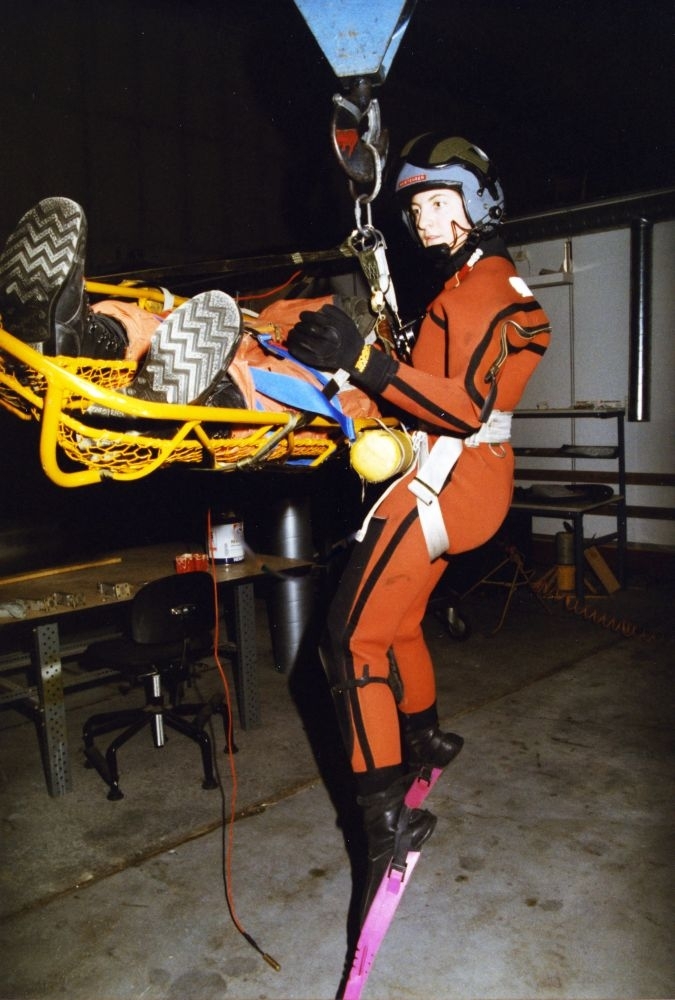 Lufthavn/Flyplass. Bodø. Flyhangar. To personer demonstrerer bruken av redningsutstyr som benyttes i Redningshelikopter.