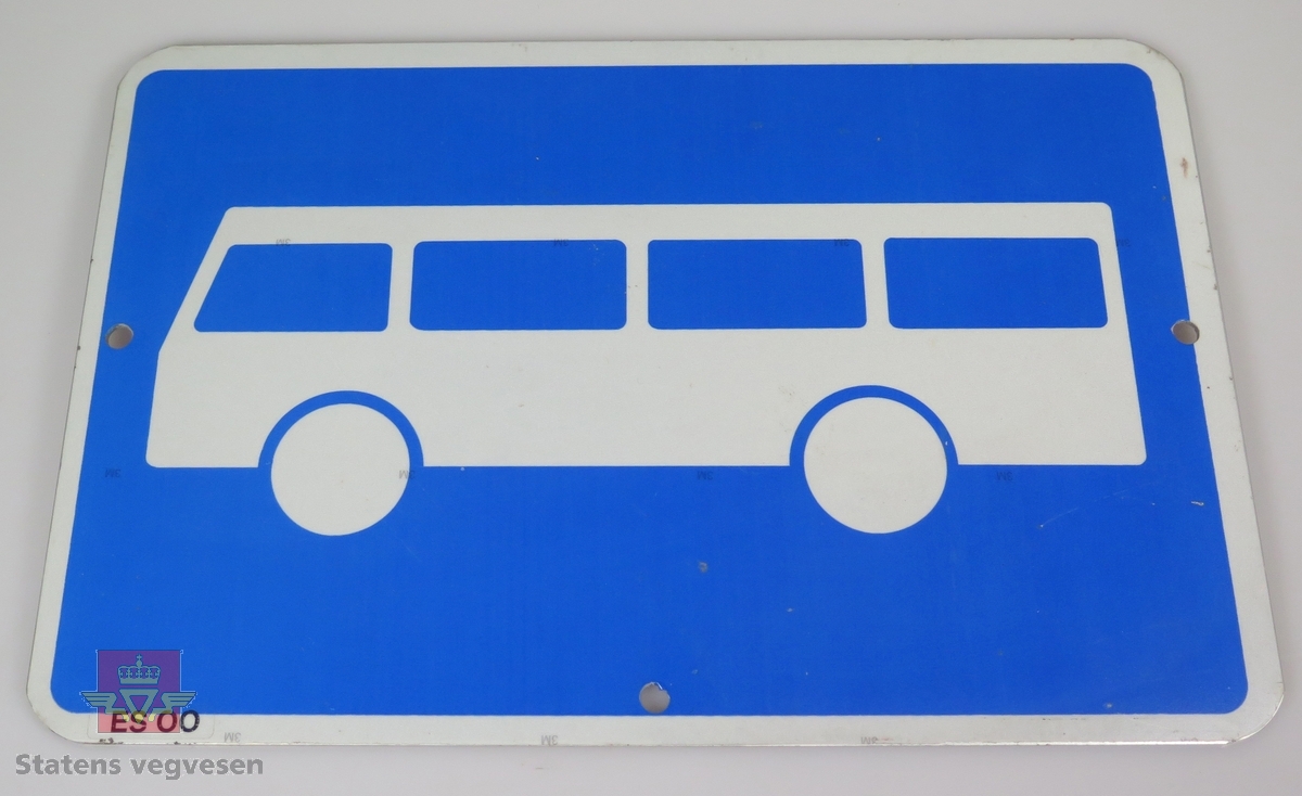Rektangulært skilt av 2 mm aluminiumsplate. 3M lysreflekterende overflate/folie på begge sider. Motivet viser en hvit buss mot blå bunn. Hvit bord langs kanten. Merket med ES 00. Tre hull for fastskruing.