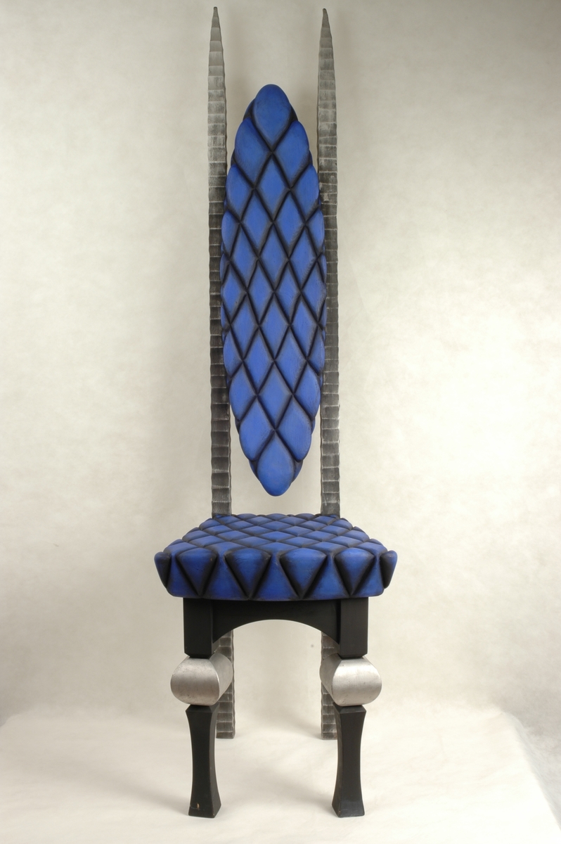 Trestol med høy rygg. Sete og rygg i blått og svart rutemønster. Rutene er skåret inn i treverket.