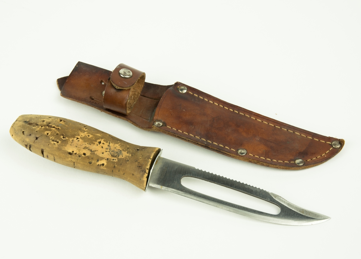 Slidkniv till fpl.18. Kniven förvaras i en läderslida. Knivens blad är av rostfritt stål. Handtaget är av kork. Ryggen på bladet är sågtandat.