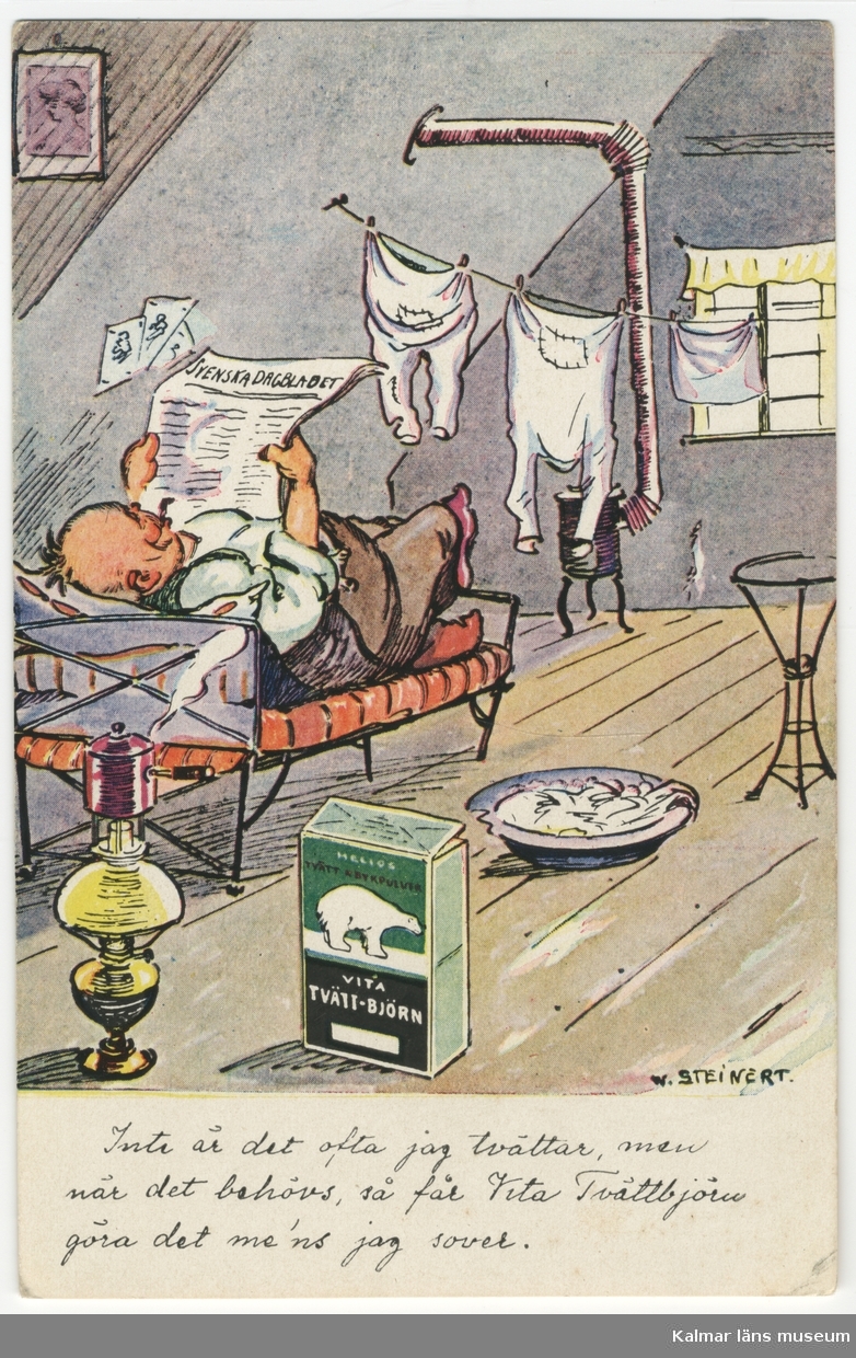 Interiör av vindsrum, där en man ligger på en järnsäng och läser Svenska Dagbladet, medan tvätten torkarpå en lina vid en kamin. I förgrunden står ett paket Vita tvättbjörn tvättmedel, en fotogenlampa och ett fat eller en balja med tvätt.