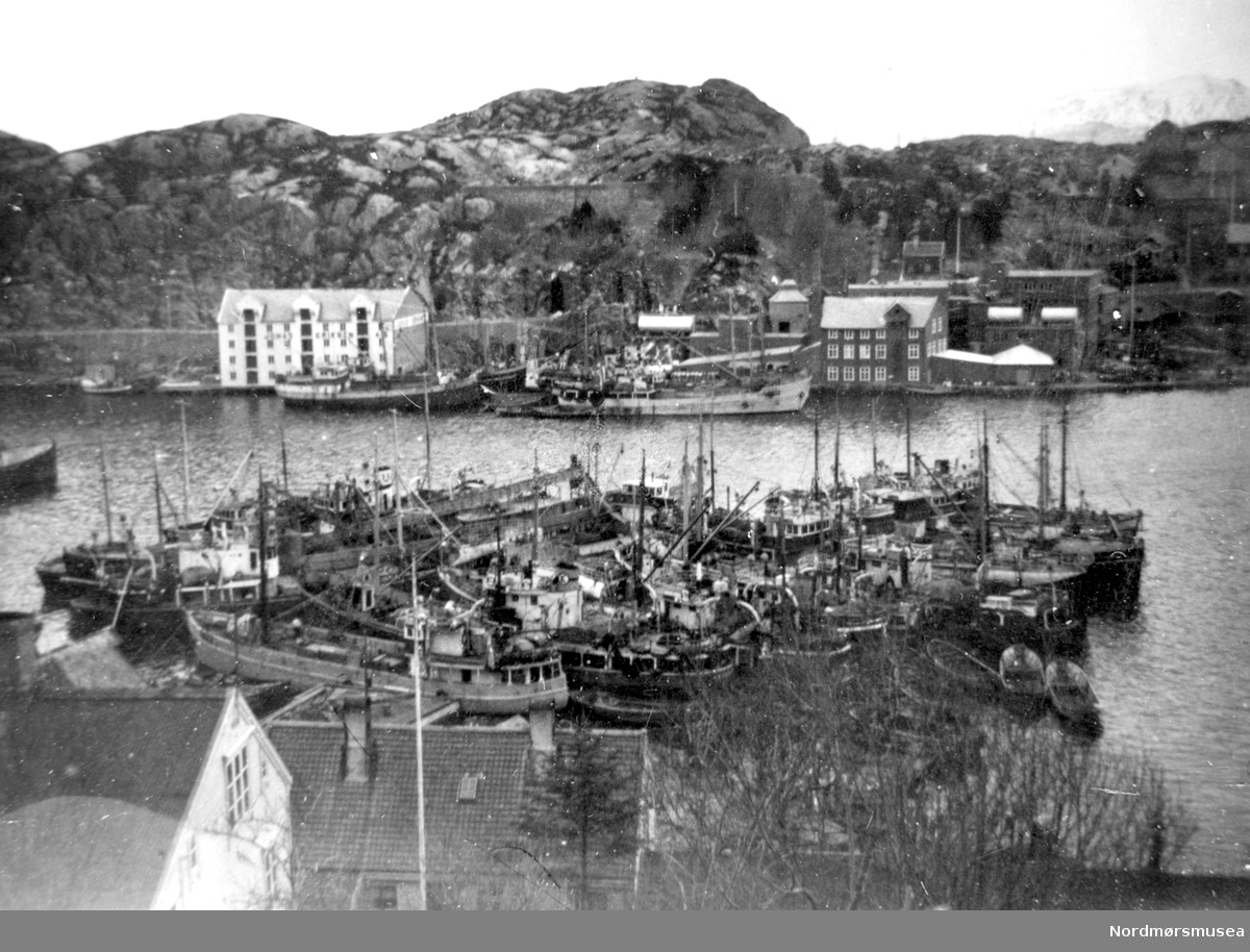 Fiskebåter foran Mellemværftet. På Goma: Jonas Eriksen-brygga og gamle Goma fabrikker (Før "Ello"-blokka) ca 1930. 
 Fra Nordmøre Museum sin fotosamling.