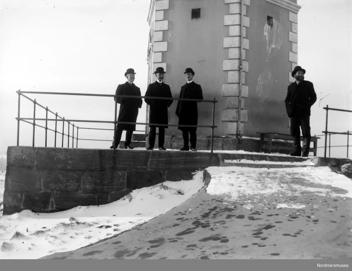 Fire menn ved Vardetårnet på St. hanshaugen på Kirkelandet i Kristiansund en vinterdag. Datering er ukjent, men trolig omkring 1920 til 1930. Fra Nordmøre Museums fotosamlinger.
