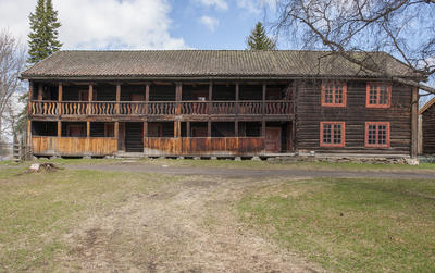 Hubredbygningen på Hedmarkstunet er en lang, brunlig tømmerbygning i to etasjer med svalgang langs hele langveggen.
