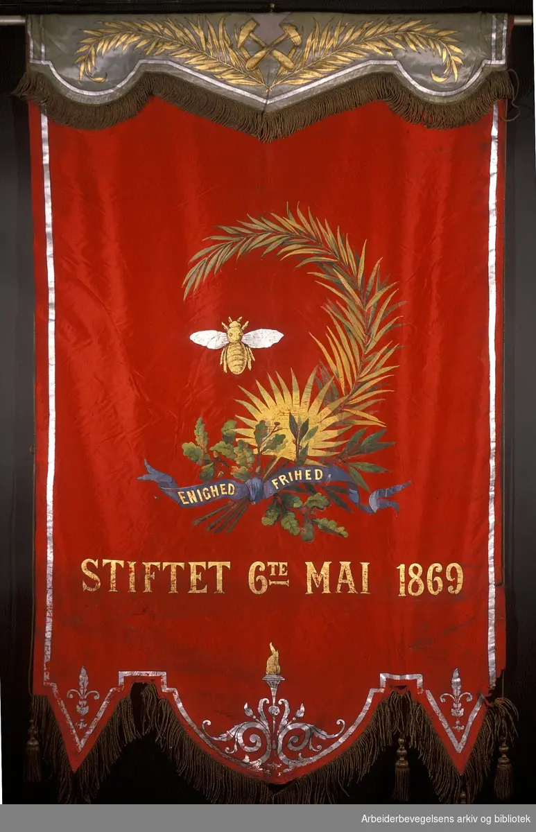 Kongsberg arbeidersamfund.Stiftet 6. mai 1869..Bakside..Fanetekst: Enighed Frihed.Stiftet 6te mai 1869