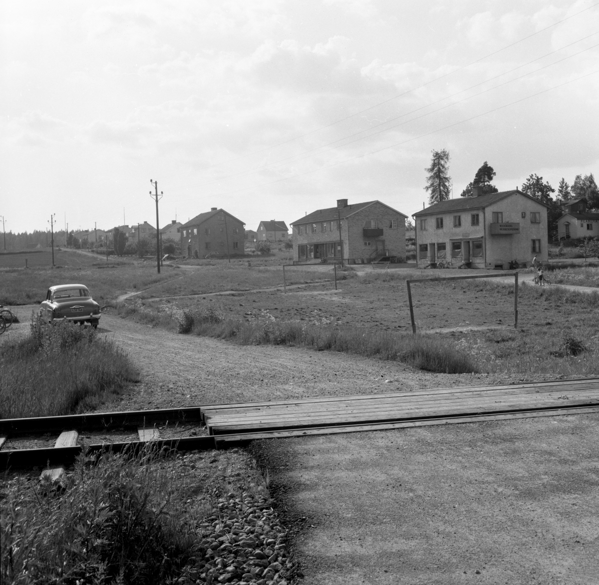 Någonstans i Värmland - från slutet av 1950-talet. Älvenäs, gatan till höger är Åkergatan. Järnvägen som syns går till vänster ner till Rayonfabriken och till höger in till Vålberg. I första byggnaden fanns Wickmans Herrekipering