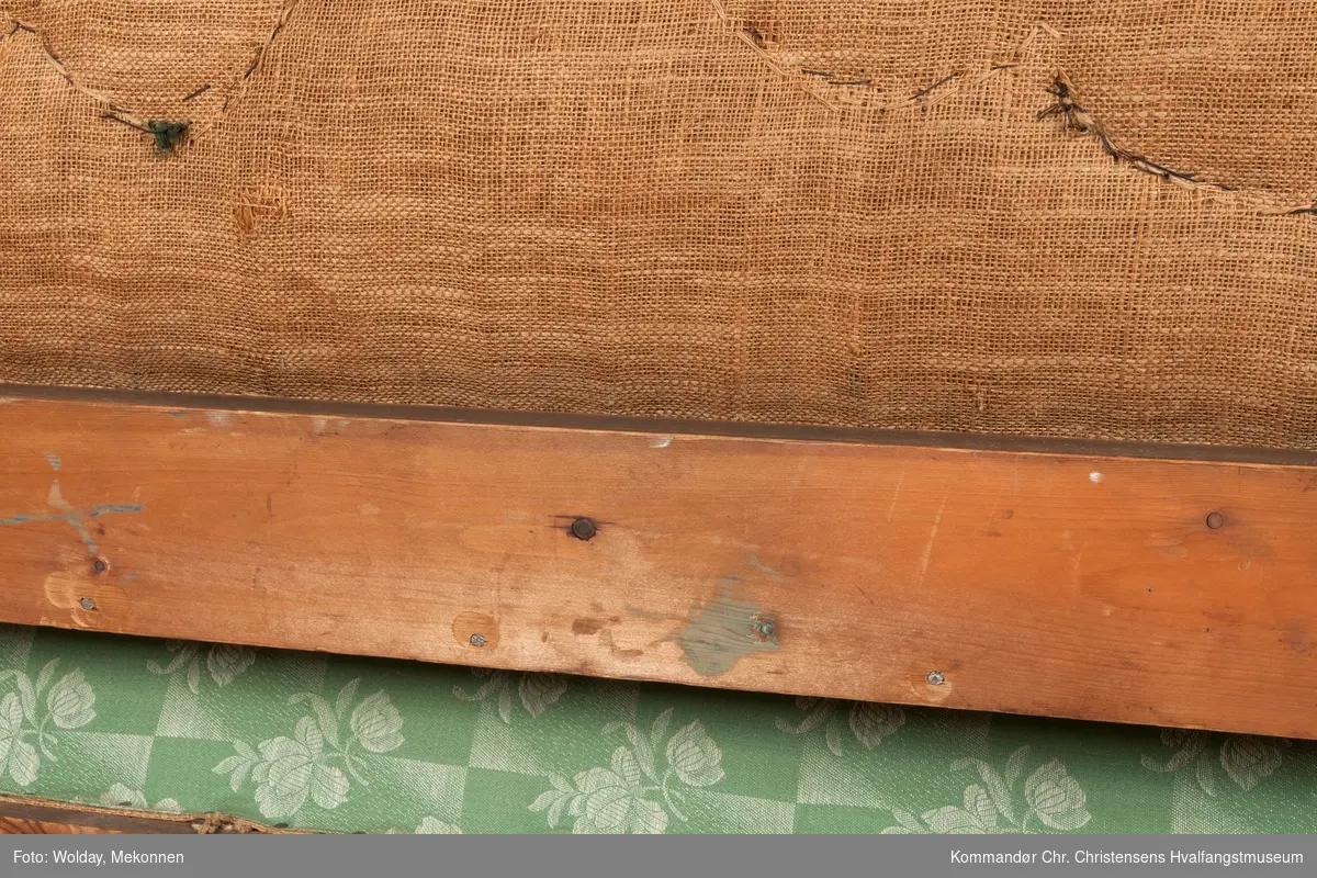 Akantusdekor i treverket. Dekor m/possementsnorer. Baksiden av sofaen er laget av et billigere treslag, der det ikke synes. Sofaen er nok ment å stå inntil en vegg. Grønt stoff ble brukt som underlag før det røde.