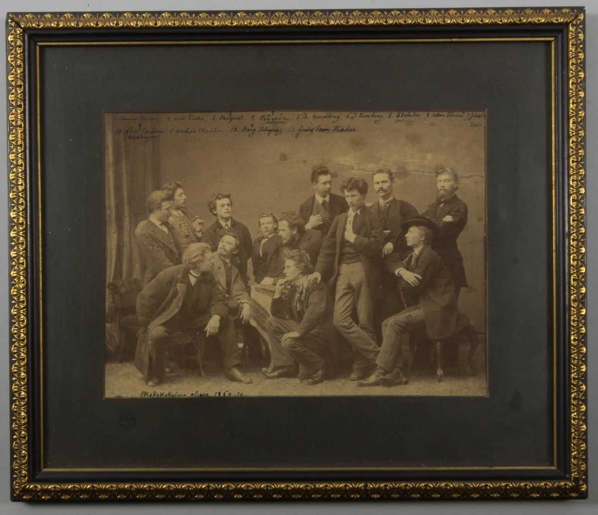 Fotografi föreställande eleverna vid Konstakademiens modellskola, samtliga män. En del står och en del sitter.
