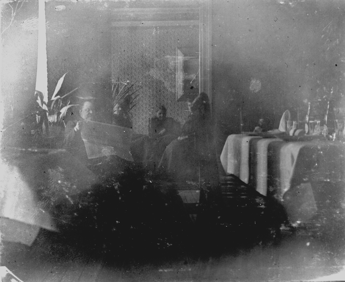 En man sitter och läser. Tre kvinnor sitter bredvid. Fotograf Alfred Bergendahl. Givare H Bergendahl.
