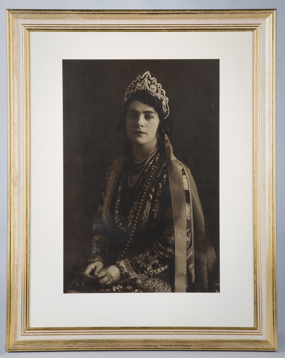 Forestiller Victoria Bachke i russisk nasjonaldrakt, rikt brodert, tiara pyntet med perler og stener og lange, flerfargede bånd.