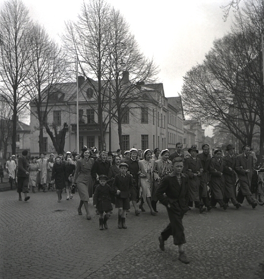 Andra dagens studenter, 1944.
Studenter och anhöriga m.fl., är på väg mot Esaias Tegnérs staty vid domkyrkan. I bakgrunden syns några av husen utmed Linnégatan, i korsningen mot Sandgärdsgatan.