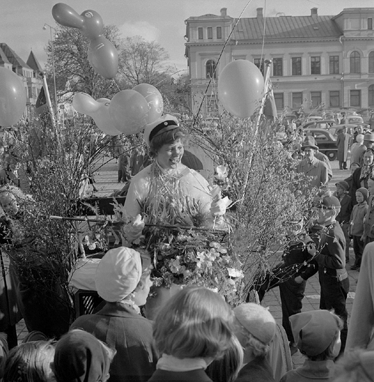 Studenterna, 1956. 
En glad kvinnlig student på en lövad vagn på Stortorget. i bakgrunden skymtar Stadshotellet.