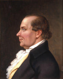 Portrett av Peder J. Cloumann. Profil. Mørk drakt, hvit skjorte med kalvekryss, lys gul vest. (Foto/Photo)