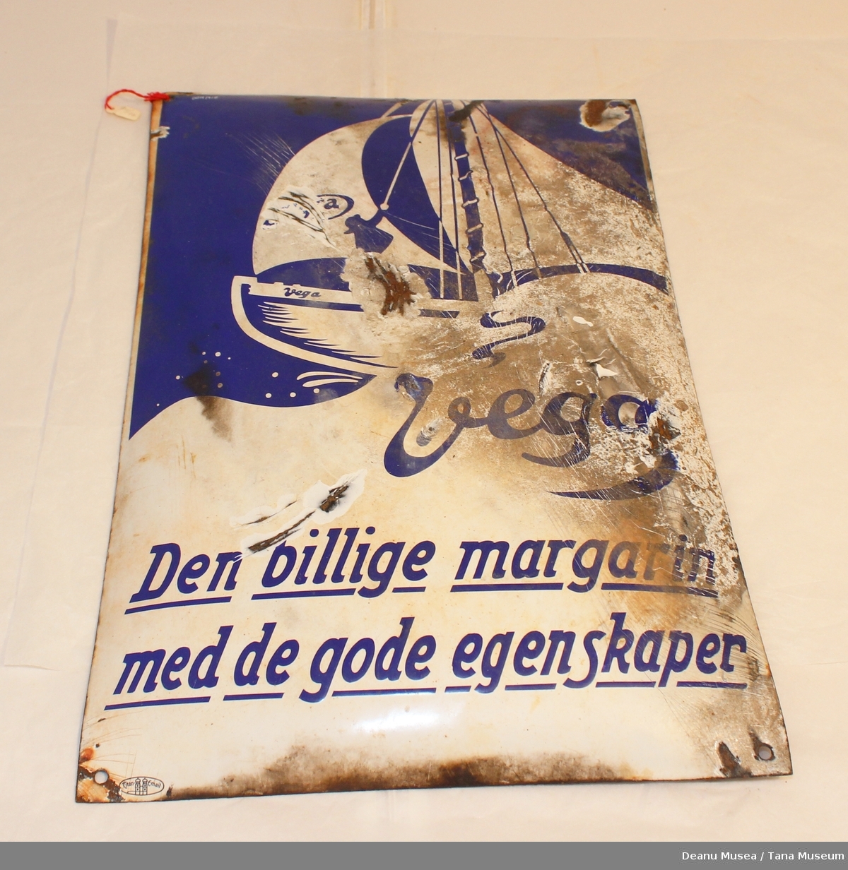 Reklameskilt for Vega margarin, blå/hvit, med motiv av en båt på havet.
