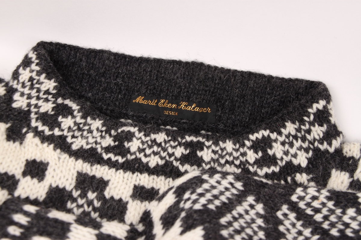 Håndstrikket ullgenser i svart og hvitt garn. Hele genseren er mønstret med åttebladsroser, blomster, ruter og doble lus.