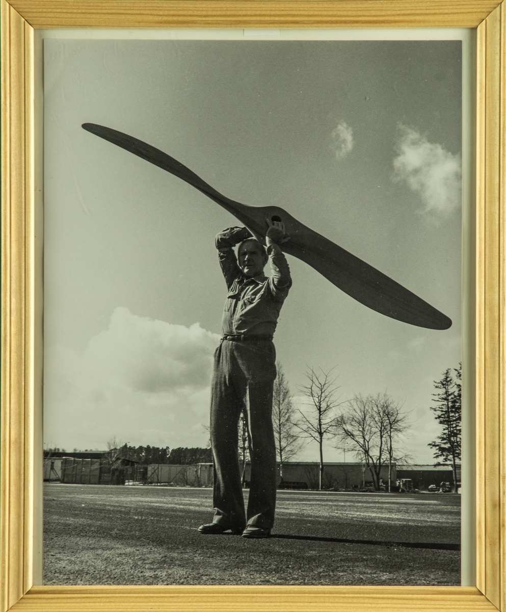 Propellersnickare Karl Erik Thellman håller upp en flygplanspropeller. Inramat foto.