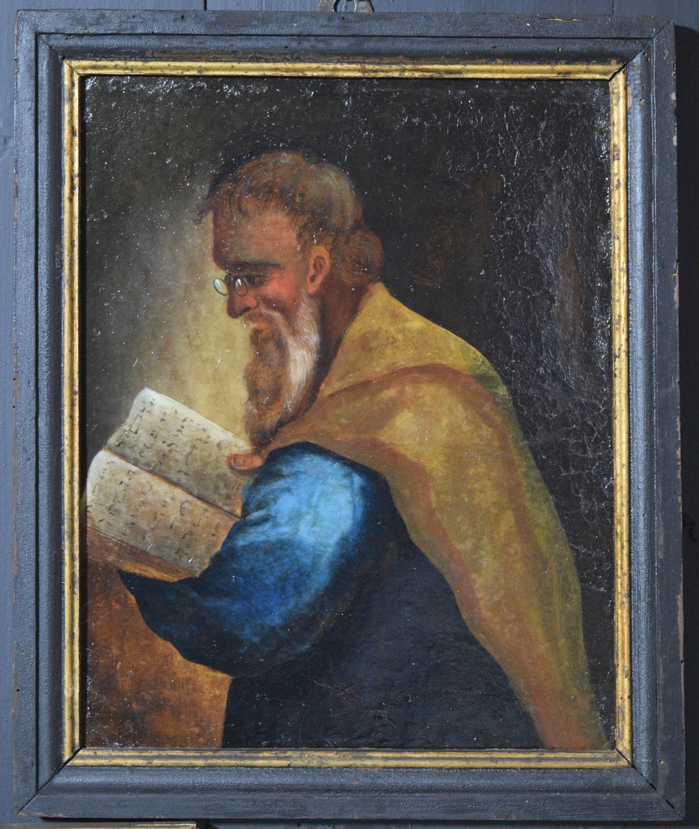 Bildet viser en eldre mann med skjegg som leser i en bok med hebraisklignende bokstaver antydet. Mannen er vendt mot venstre og sees tilnærmet i profil. Haner kledd i en blå kjortel(?) og han har en gulbrun kappe over skuldrene. På nesten sitter en lorgnett.