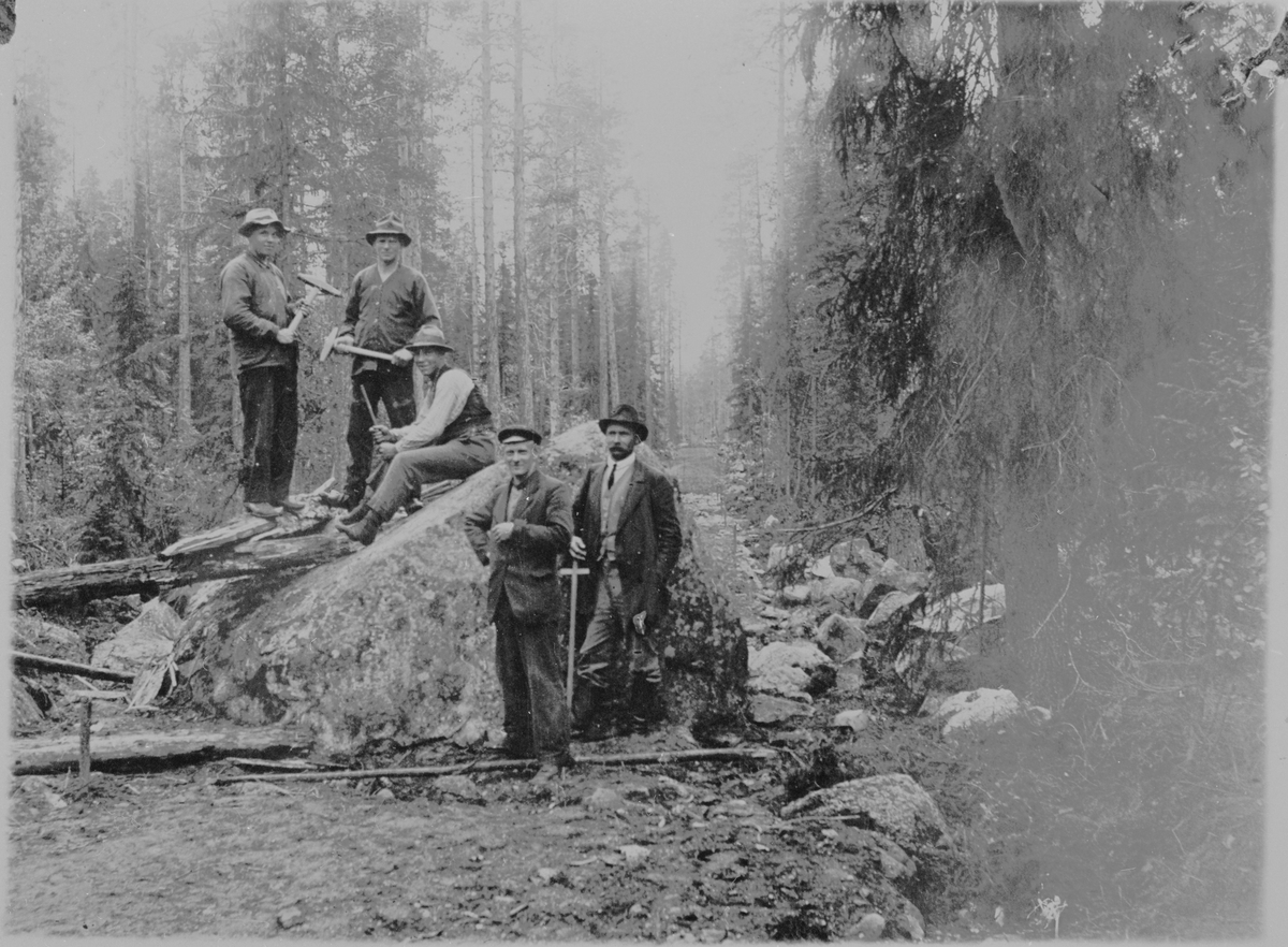 Män med släggor, som bryter sten i skogen.