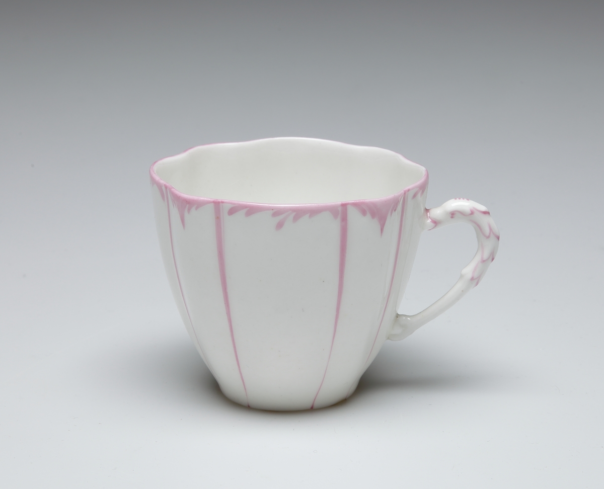 Kaffekopp, porslin. Vit med rosa, lodräta linjer. Vågig kant med rosa bård. 

Inskrivet i huvudkatalog 1968.