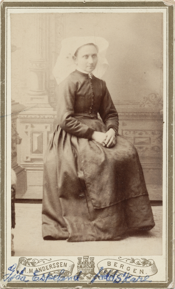 Visittkortfoto av kvinne i knappetrøye og hardangerskaut.