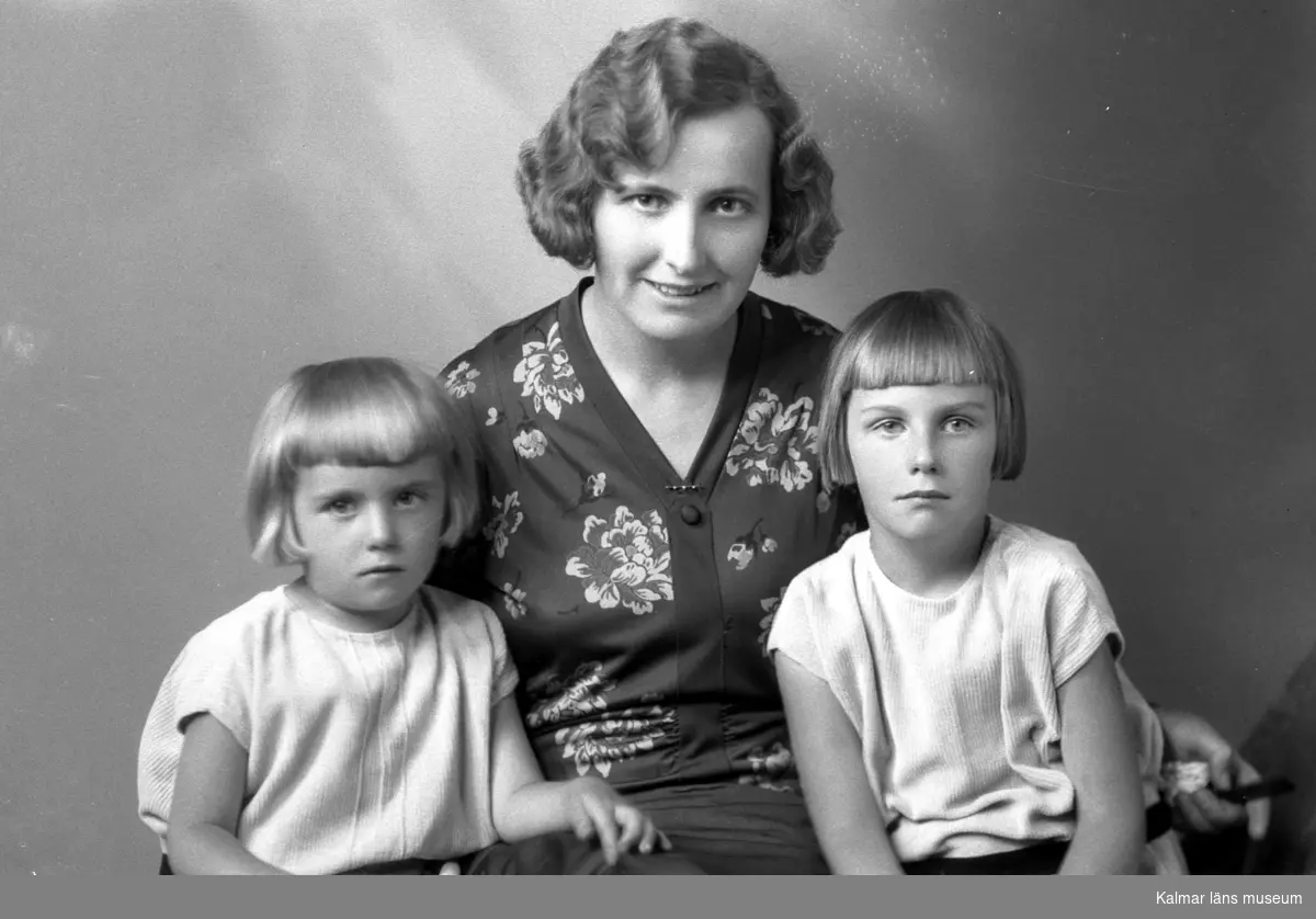 Ateljébild på en kvinna med två flickor. Enligt Walter Olsons journal är bilden beställd av fru Helga Gratte.