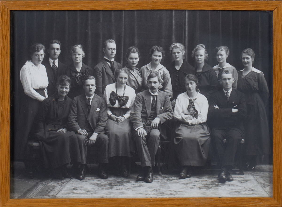 Gruppefoto av farmasøytisk studentkull. Gruppe med fire unge menn, elleve unge damer og en eldre mann i midten.