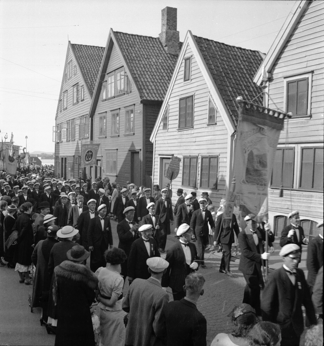 Tyssedal Mannskor med flere defilerer forbi bryggehus i Stavanger, på veg til Bjergstad
