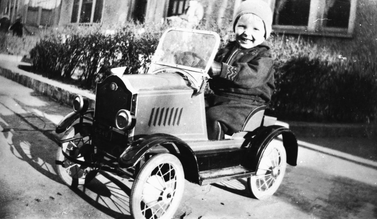 Portrettfotografi av en liten gutt i en tråbil.