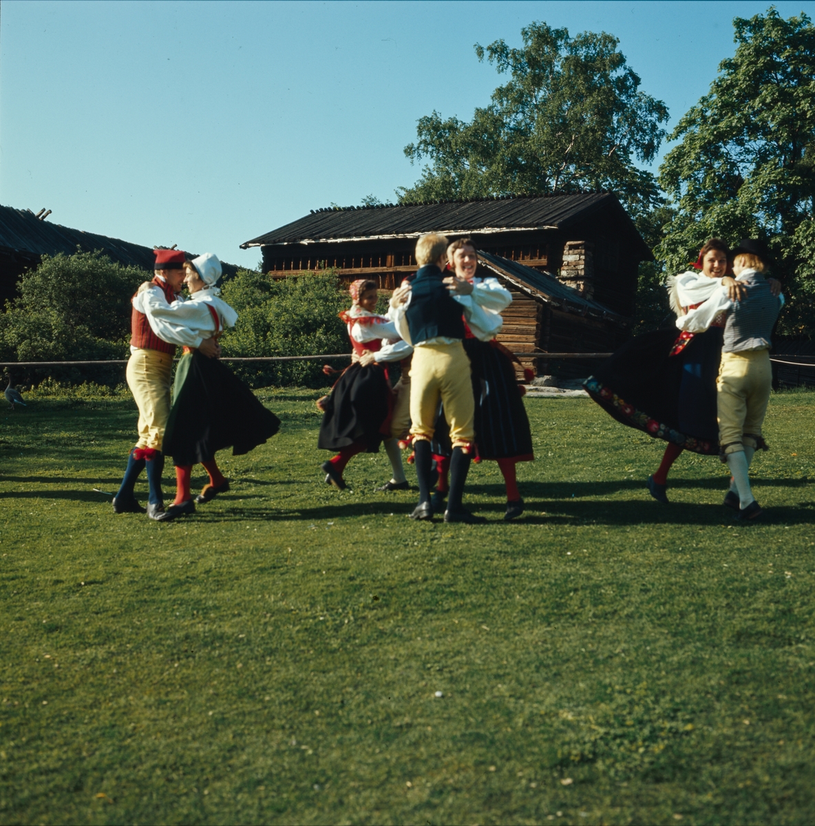 Ett folkdanslag dansar på Orsakullens gräsplan.