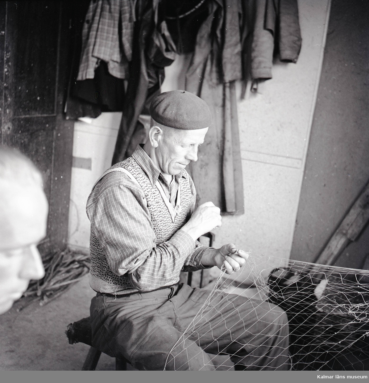 En man som lagar ett fiskenät på Stensö fiskeläge.