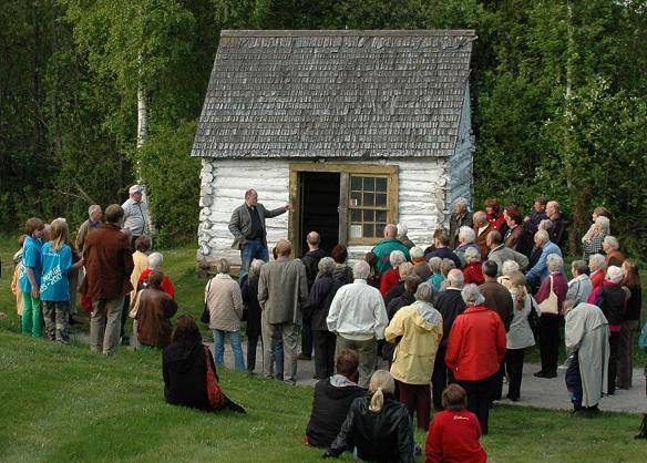 A man tells a large group of people about the history of Gundersenstua located in the open-air museum.