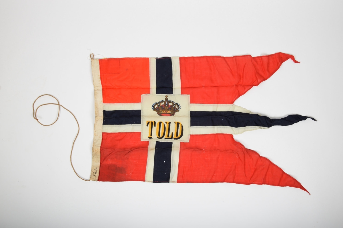 Norgesflagg med "TOLD" skrevet på midten. Over teksten er det avbildet en krone. Bånd til oppheng i den venstre kortsiden. 3 spisser i høyre side.