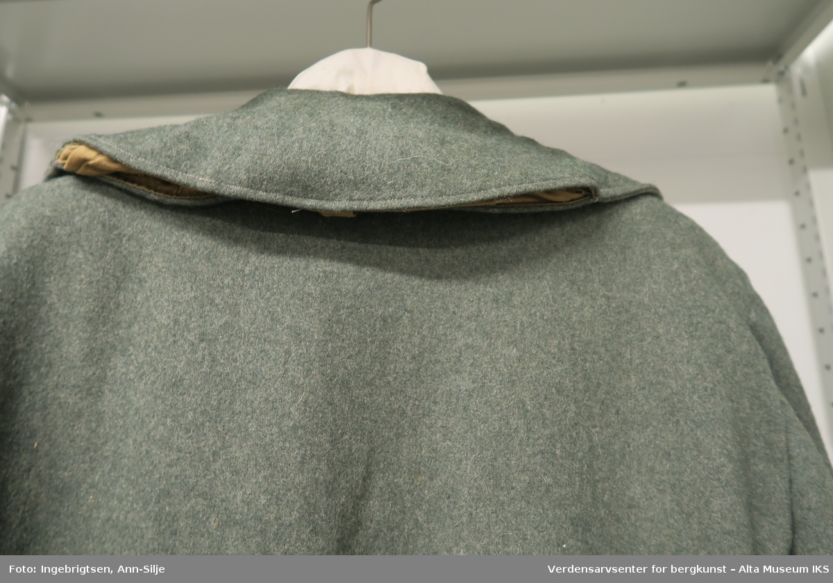 Dobbeltspent jakke med saueskinnsfor. I kragen er det innfelt hette i tøy. Knappene har relieffer av anker - emblemet til den tyske kriegsmarine.