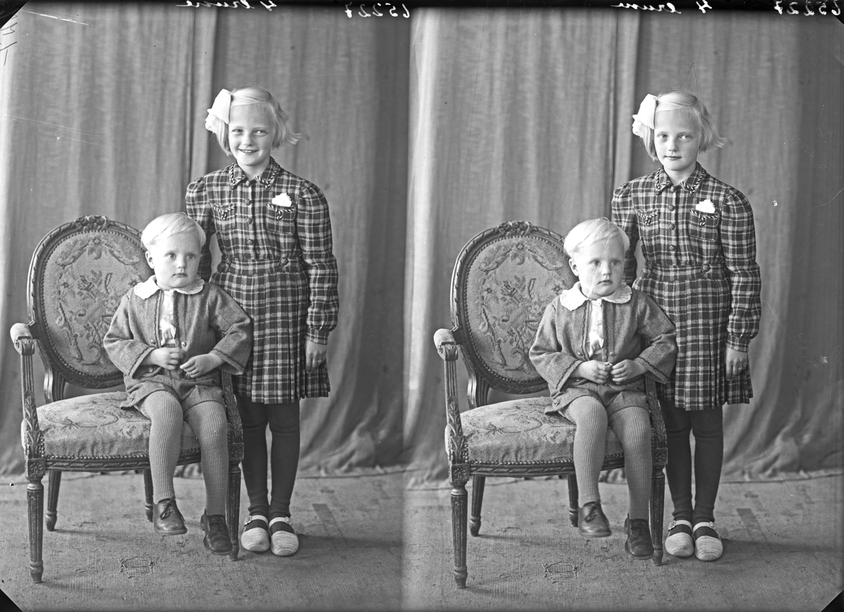 Portrett. To barn. En ung gutt sittende på en stol  og en pike stående ved siden av. Bestillt av Reidar Rasmussen. Skorpen. Onarheim.