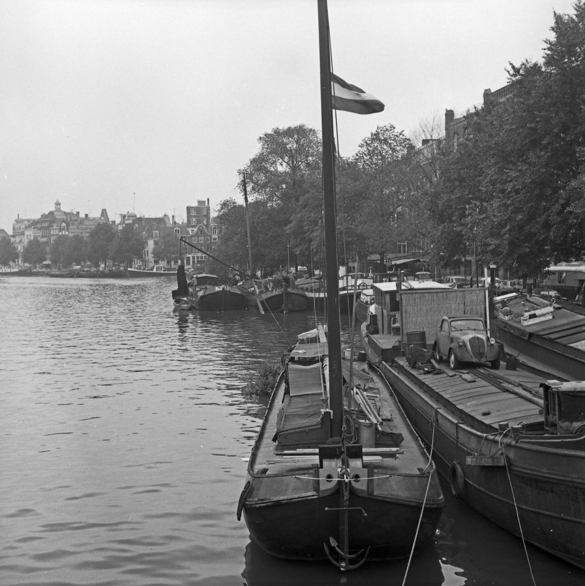 Sentrumsgater og kanaler i Amsterdam. Kanalbåter side om side med biler.