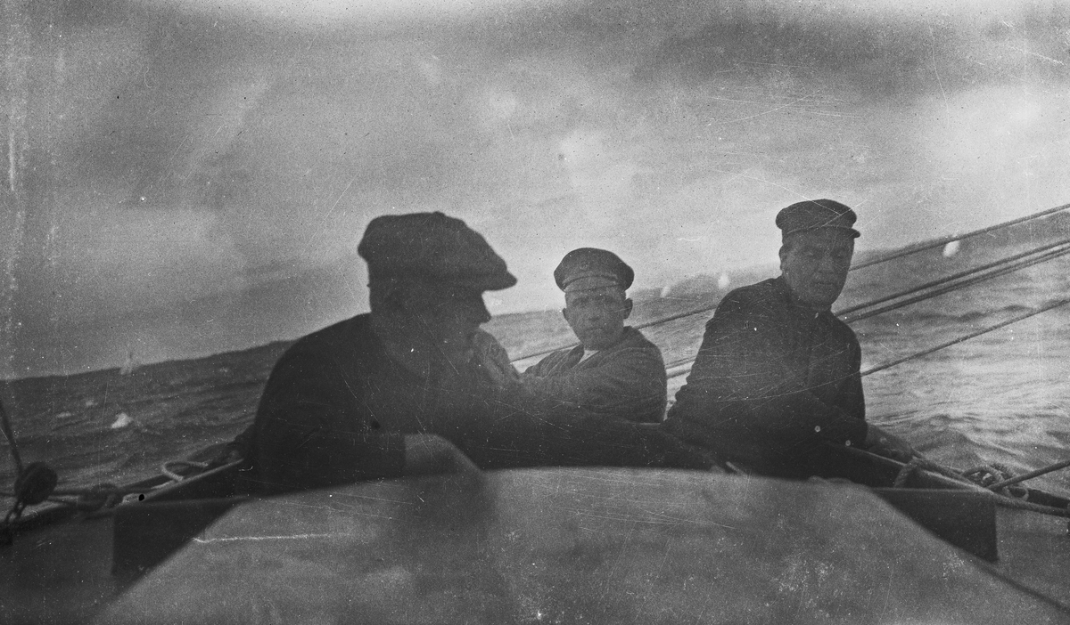 På havet. Tre menn i en seilbåt. Hverdagsfoto.