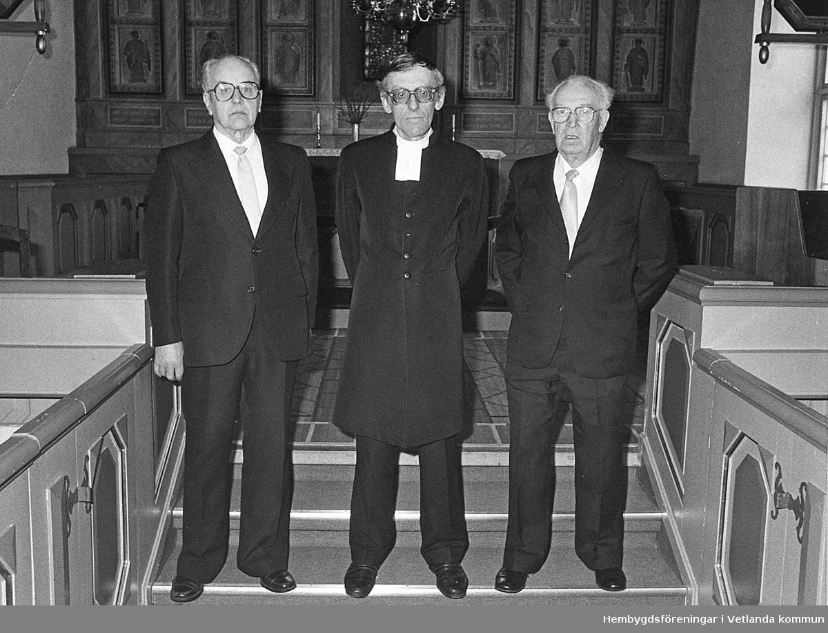 Bilden är tagen 1988 i Bäckseda kyrka. Kyrkvärdarna Karl-Fredrik Johansson och Börje Josefsson står på var sin sida om kyrkoherden Sven-Erik Degaardt.