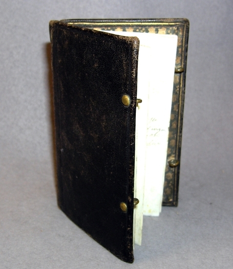 Anteckningsbok som tillhört Kung Carl XII, (1697-1718). Boken är tillverkad av Jacob Ladmiral, Amsterdam.

Pappärmar klädda med svart skinn, mässing beslag, 6 st blad gjorda av elfenben fastsatta med tråd. 
Med boken följer små noteringar.