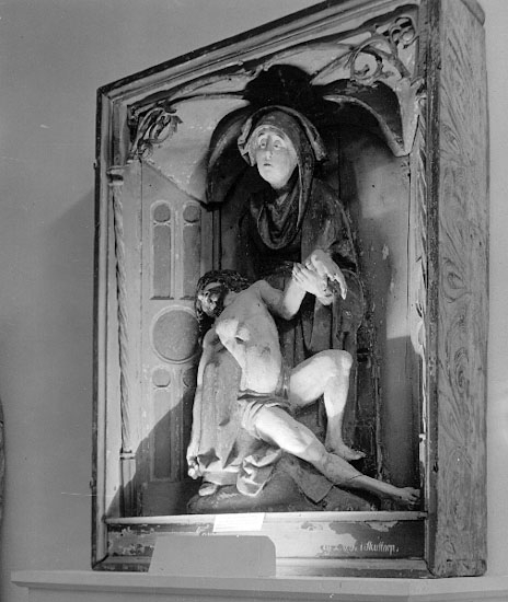 I Västergötlands museums samlingar. 
Inv.nr. 7798.

PietÃ , framställning av den sörjande jungfru Maria, sittande med den döde Kristus i sitt knä. Motivet har sin bakgrund i senmedeltidens passionsmystik och uppstod i Rhenområdet i början av1300-talet. Det blev därefter vanligt i både måleri och skulptur. En ensam sörjande Maria kallas mater dolorosa. 
http://www.ne.se/jsp/search/article.jsp?i_art_id=283310